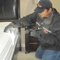 Bed bug inspection technician checking a mattress and bed frame for signs of infestation in Toledo, OH
