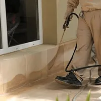 General pest control technician spraying exterior perimeter around a home in Toledo, OH