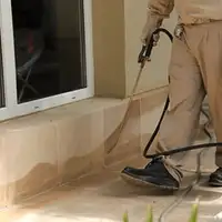 General pest control technician spraying exterior perimeter around a home in Toledo, OH