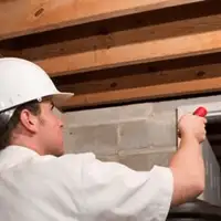 Termite inspection technician checking a basement wall and framing for termite activity in Toledo, OH